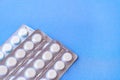 Aspirin in a blister on top. Vitamin C pills in a pack. White tablets in a blister on a blue background close-up with soft focus.