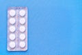 Aspirin in a blister on top. Vitamin C pills in a pack. White tablets in a blister on a blue background close-up with soft focus.