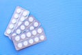 Aspirin in a blister on top. Vitamin C pills in a pack. White tablets in a blister on a blue background close-up with soft focus.