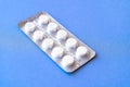 Aspirin in a blister on top. Vitamin C pills in a pack. White tablets in a blister on a blue background close-up with soft focus. Royalty Free Stock Photo