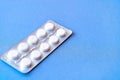 Aspirin in a blister on top. Vitamin C pills in a pack. White tablets in a blister on a blue background close-up with soft focus. Royalty Free Stock Photo