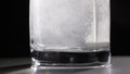 Aspirin tablet in glass of water over black