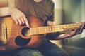 An aspiring young musician plays a tune on an old dilapidated acoustic guitar Royalty Free Stock Photo