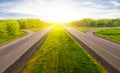 aspralt highway among green fields to the sunset