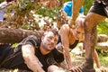 Assault course competitor helping others crawl under nets