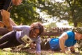 Assault course competitor helping others crawl under nets Royalty Free Stock Photo