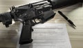 Assault rifle with pen and public domain background check form