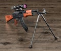 Assault rifle with telescopic sight and bipod on the wooden table, 3D rendering