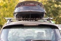 Assembled and closed, roomy roof rack or roof box against a blurred background of green leaves. Back view