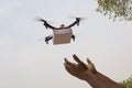 Assembled Drone quadcopter delivering a package and hands receiving the parcel