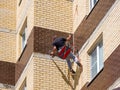 Assemblers drill a wall at home using climbing equipment