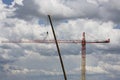 Assembling of crane on dramatic cloudy background. Dangerous height situation.