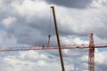 Assembling of crane on dramatic cloudy background. Dangerous height situation. Royalty Free Stock Photo