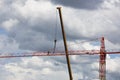 Assembling of crane on dramatic cloudy background. Dangerous height situation.