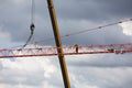 Assembling of crane on dramatic cloudy background. Height tower crane.