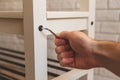 Assembling of furniture, closeup hex wrench in hand, furniture screw screwed into board of bench Royalty Free Stock Photo
