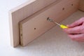 Assembling furniture, mens hand tightens screw with a screwdriver