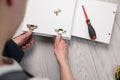 Assembling furniture. A worker inserts a hinge into a wooden closet door. Adjustment of fittings, door hinges.