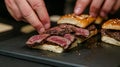 assembling gourmet sliders with wagyu beef, hands in focus . Royalty Free Stock Photo