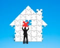 Assembling last red puzzle into house shape Royalty Free Stock Photo