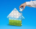 Assembling puzzles in house shape in blue background Royalty Free Stock Photo