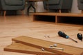 Assembly of furniture, the different parts and pieces of furniture arranged on the wooden floor. DIY furniture assembly concept Royalty Free Stock Photo