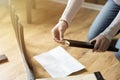 Assembly of wooden furniture, a woman putting together the wooden parts of the dining chair, using instruction. and a furniture s Royalty Free Stock Photo