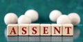 ASSENT - word on wooden cubes on a green background with wooden balls