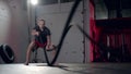 Assertive man doing exercises with battle rope, ruthlessly effective workout.