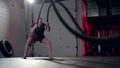 Assertive man doing exercises with battle rope, ruthlessly effective workout.