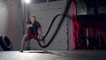 Assertive man doing exercises with battle rope, ruthlessly effective workout.