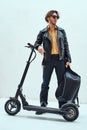 Assertive and rich young man posing on a scooter in a bright studio, looking cool Royalty Free Stock Photo