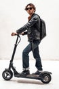 Assertive and rich young man posing on a scooter in a bright studio, looking cool Royalty Free Stock Photo