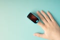 Assessment of the function of the respiratory system. Female finger in a pulse oximeter on a blue background with copyspace