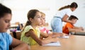 Assiduous focused tween girl sitting with pen and notebook at lesson Royalty Free Stock Photo