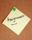 Assignment witten on note stuck to corkboard Royalty Free Stock Photo