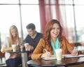 This assignments a cinch. A beautiful young university student using her smartphone in a coffeee shop while studying. Royalty Free Stock Photo