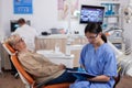 Assistant in dentist cabinet during elderly woman oral hygiene check up