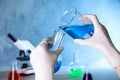 Assistant pouring sample into glass flask in chemistry laboratory