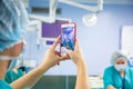 Assistant shooting on the smartphone from the operating room. Medical Team Performing Surgical Operation in Modern Royalty Free Stock Photo