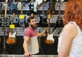 Assistant showing customer guitar at music store