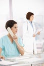 Assistant taking phone call, doctor in background Royalty Free Stock Photo