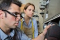 assistant watching cobbler hold shoe against polishing wheel