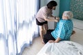 Assisting in dressing,female caregiver taking care of helping elderly patient get dress,wear clothes for senior grandmother,old Royalty Free Stock Photo