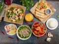 Pho bo, pho tom, noodles, spring rolls, tom yam, rice, mango shake on beautiful black stone table top view Royalty Free Stock Photo