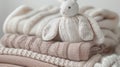 Assorted baby jersey sweaters and textiles in gentle beige pastel shades, paired with a charming bunny plush toy