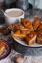 Assorted baklava. A Turkish ramadan arabic sweet dessert on a decorative plate, with coffee cup in the background. Middle eastern Royalty Free Stock Photo