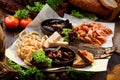 Assorted beer snacks: onion rings, smoked fish, mussels and shrimps on tray on sackcloth among vegetables