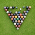 Assorted bocce balls are arranged in a triangular formation on a well-maintained grass surface Royalty Free Stock Photo