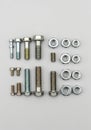 Assorted bolts and nuts of various sizes are arranged neatly on a plain gray Royalty Free Stock Photo
